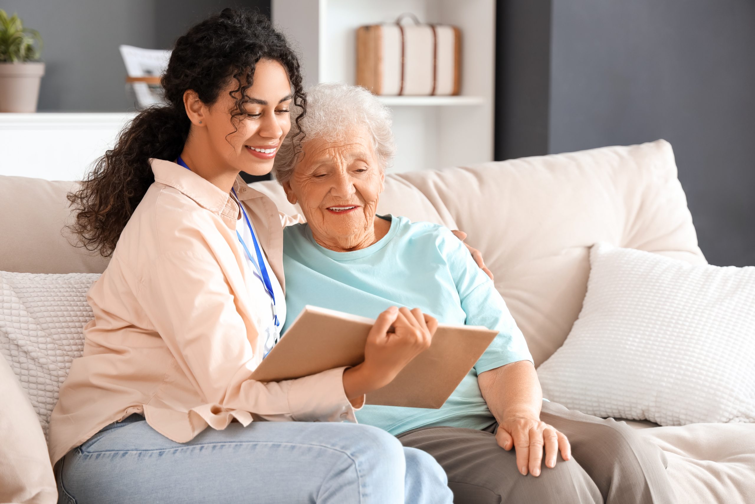 Young woman sitting on the couch reading to an elderly woman